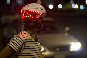 Femme qui freine de nuit avec casque lumineux Be Mojoo