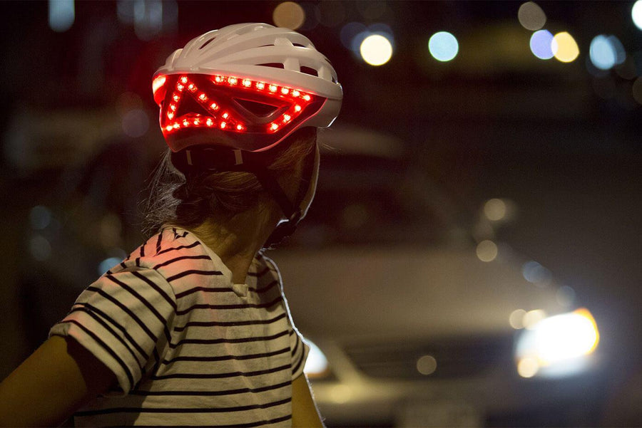 Femme qui freine de nuit avec casque lumineux Be Mojoo