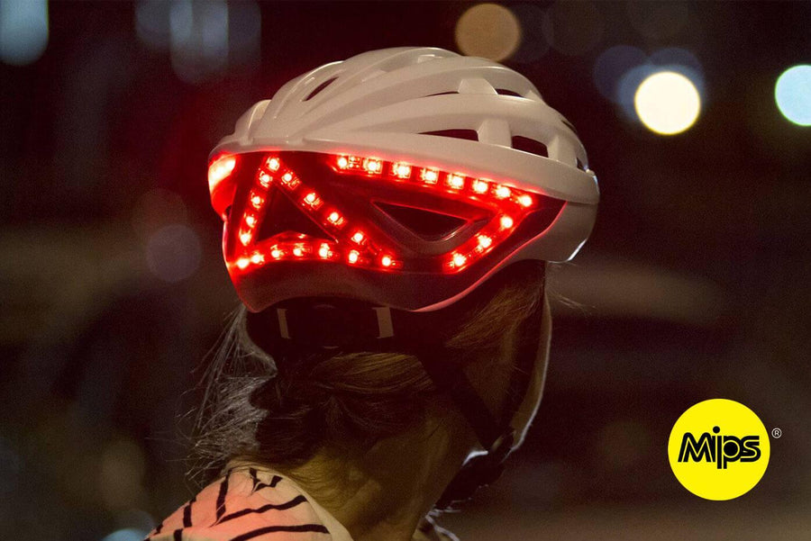 Femme qui freine de nuit avec casque lumineux Be Mojoo avec technologie MIPS